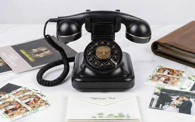 Telefon retro negru cu disc rotativ și accente aurii, folosit ca audio guestbook. Este așezat pe o suprafață de marmură, înconjurat de fotografii de nuntă, plicuri "Mariage Fest" și un album foto din piele.