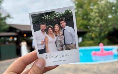 Fotografie polaroid de la nunta în aer liber, in Bucuresti facuta la cabina foto , ținută de o mână, cu mirii și prietenii lângă o piscină cu flamingo roz.